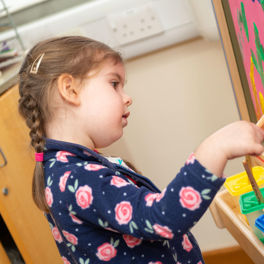A child painting on an easel