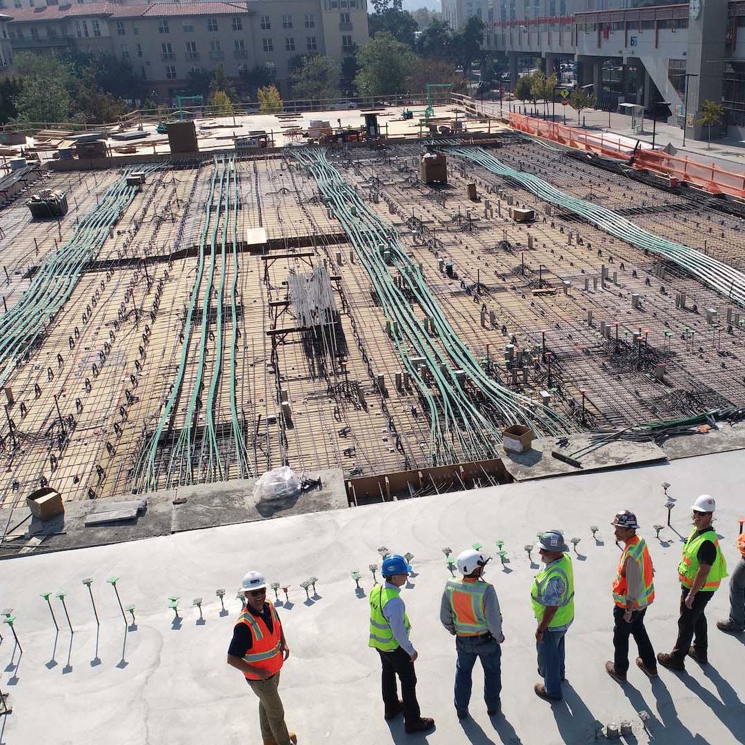 A line of workers in hard hats and bright vests on a construction site