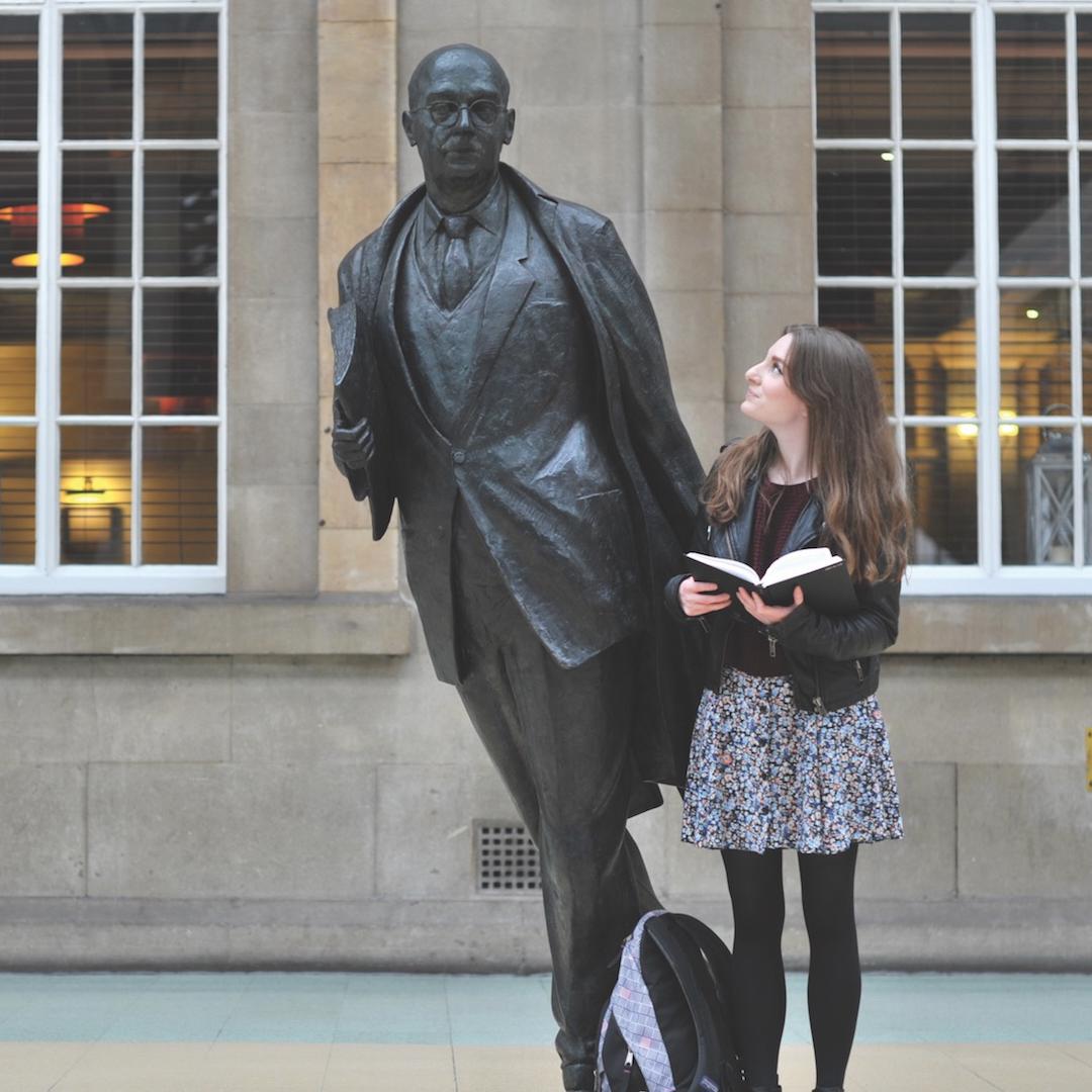 An english student stood with statue of Philip larkin in the city's rail station